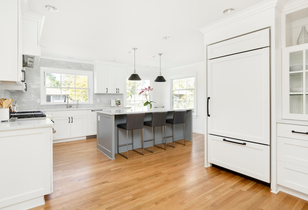 Inspiration for a contemporary l-shaped light wood floor and brown floor kitchen remodel in Portland with shaker cabinets, white cabinets, gray backsplash, glass tile backsplash, paneled appliances, an island, white countertops and quartz countertops