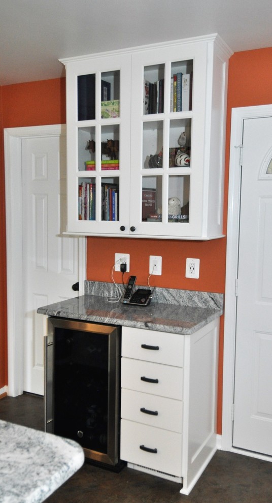Imagen de cocina moderna de tamaño medio con fregadero bajoencimera, puertas de armario blancas, encimera de granito, salpicadero negro, electrodomésticos de acero inoxidable y suelo vinílico