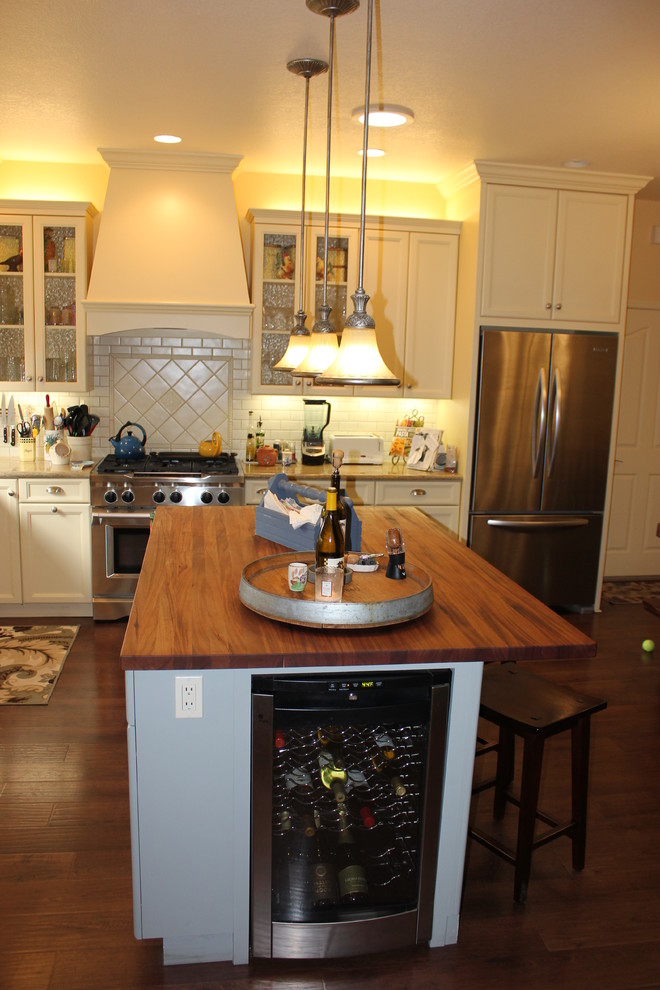 Klassisk inredning av ett mellanstort kök, med luckor med infälld panel, vita skåp, bänkskiva i koppar, vitt stänkskydd, stänkskydd i tunnelbanekakel, rostfria vitvaror, mellanmörkt trägolv, en köksö och en rustik diskho