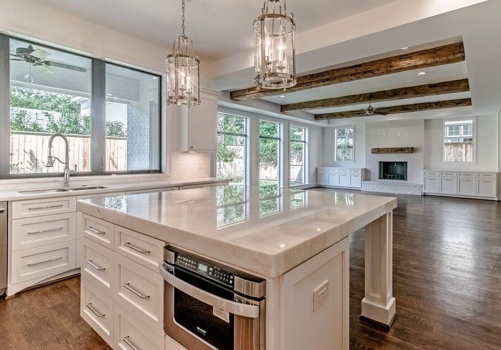 Kitchen - mid-sized traditional u-shaped kitchen idea in Houston with shaker cabinets, white cabinets, quartzite countertops, white backsplash, stainless steel appliances and an island