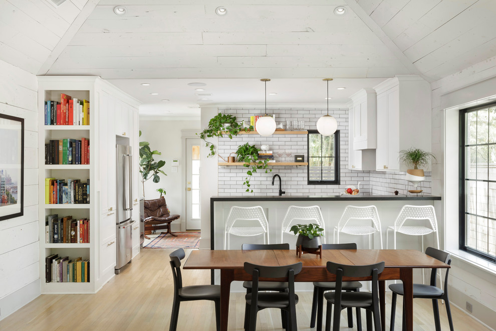 Farmhouse u-shaped light wood floor and beige floor eat-in kitchen photo in Houston with shaker cabinets, white cabinets, white backsplash, a peninsula and black countertops