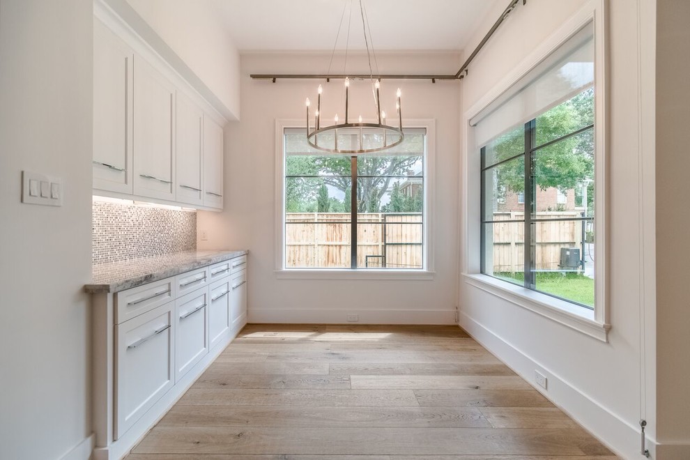 Inspiration for a large transitional l-shaped light wood floor and brown floor open concept kitchen remodel in Houston with a double-bowl sink, shaker cabinets, white cabinets, quartzite countertops, gray backsplash, glass tile backsplash, stainless steel appliances and an island