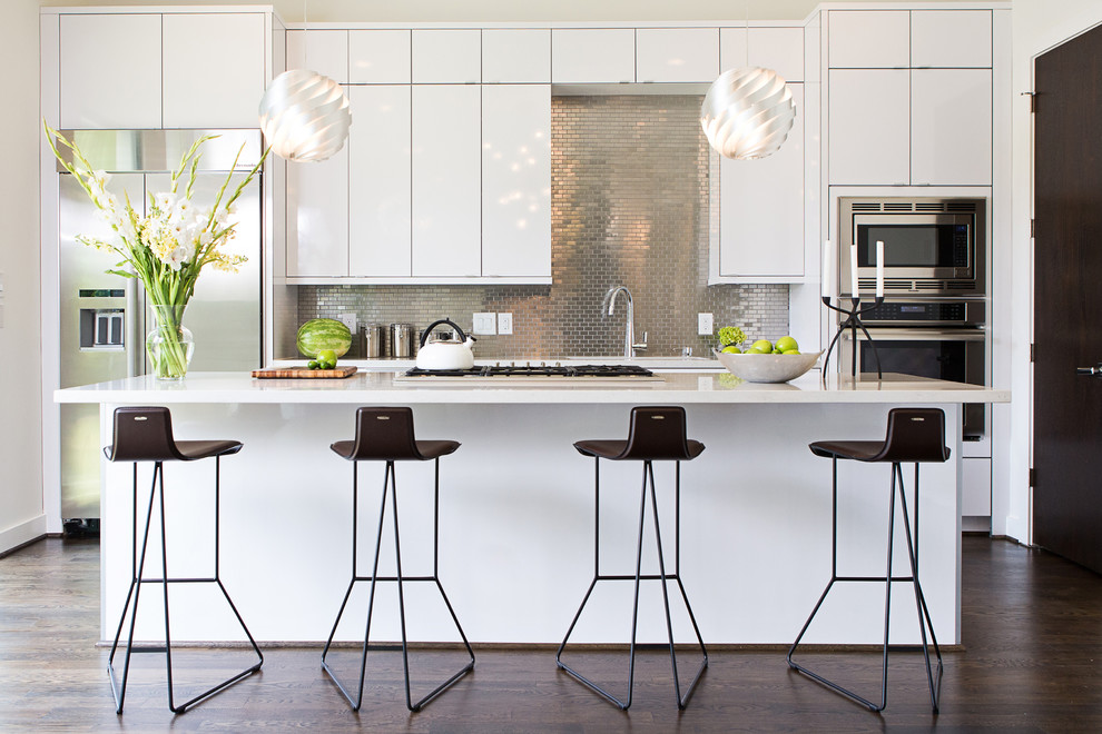 Moderne Küche mit flächenbündigen Schrankfronten, weißen Schränken, Küchenrückwand in Metallic, Rückwand aus Mosaikfliesen, Küchengeräten aus Edelstahl, dunklem Holzboden und Kücheninsel in Houston
