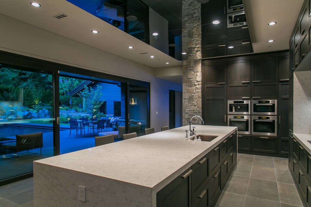 Example of a large minimalist galley ceramic tile eat-in kitchen design in Vancouver with a single-bowl sink, recessed-panel cabinets, dark wood cabinets, marble countertops, gray backsplash, stone slab backsplash, stainless steel appliances and an island
