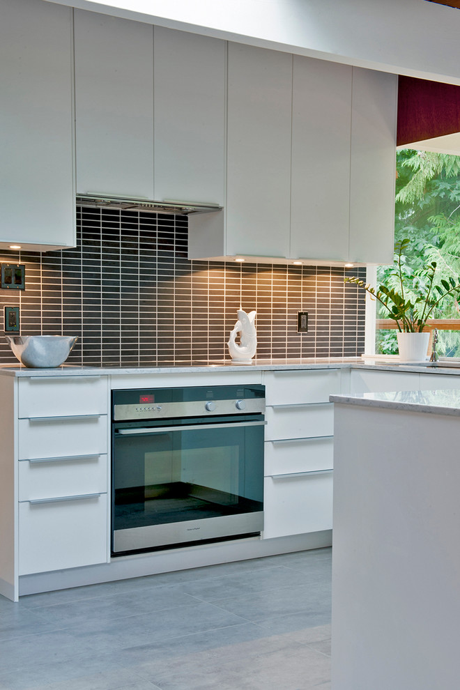Photo of a medium sized midcentury u-shaped kitchen/diner in Vancouver with a built-in sink, flat-panel cabinets, white cabinets, engineered stone countertops, black splashback, metro tiled splashback, stainless steel appliances and ceramic flooring.