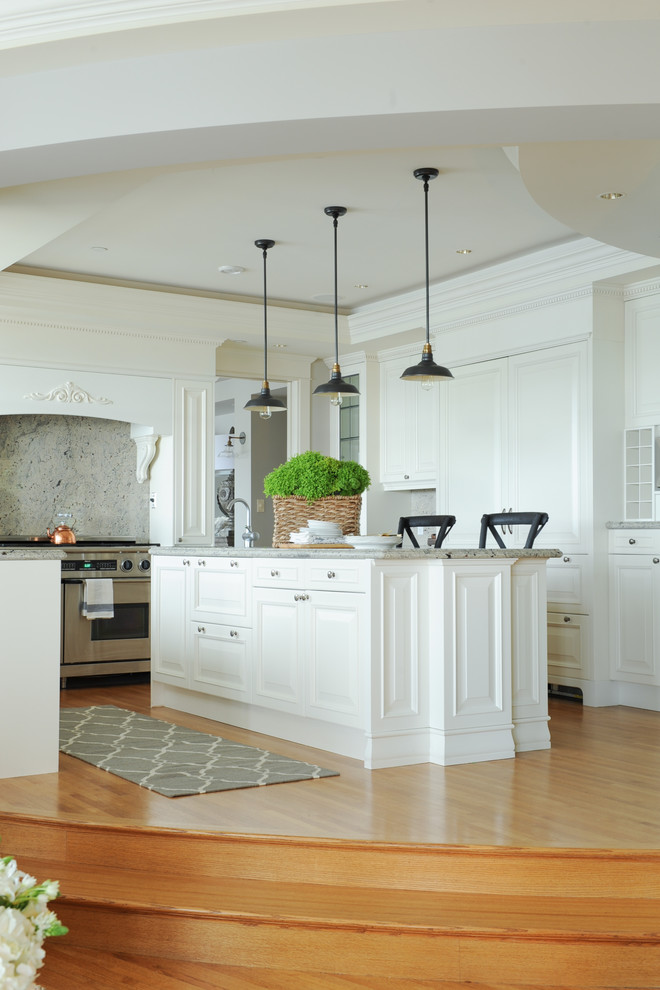 Inspiration för ett stort maritimt kök, med en integrerad diskho, luckor med upphöjd panel, vita skåp, marmorbänkskiva, grått stänkskydd, stänkskydd i marmor, rostfria vitvaror, ljust trägolv, en köksö och brunt golv