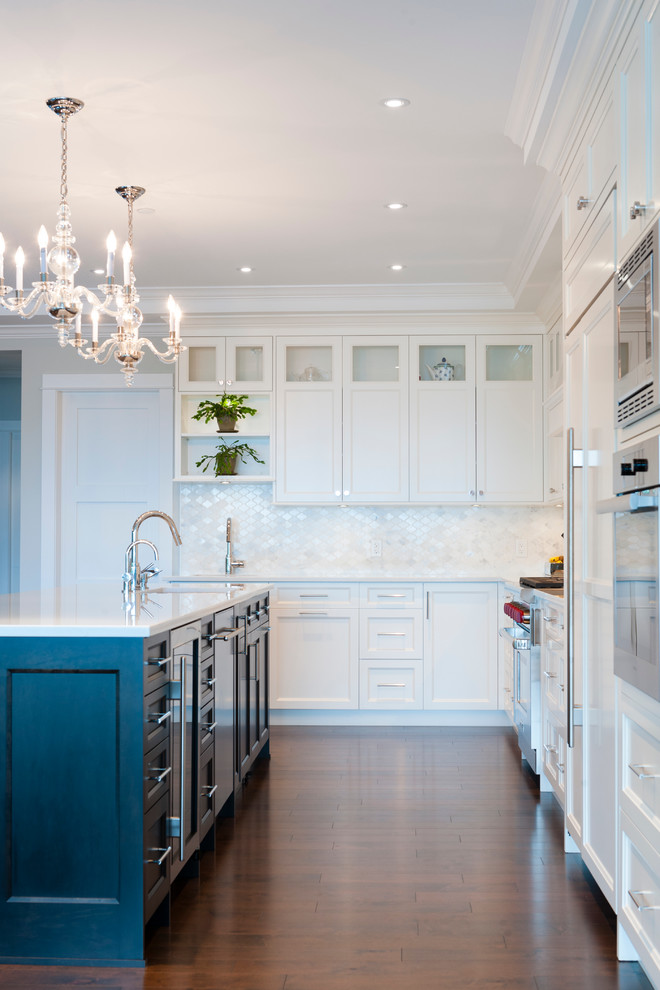 Photo of an expansive classic l-shaped kitchen in Vancouver with a submerged sink, shaker cabinets, white cabinets, marble worktops, white splashback, stone tiled splashback, dark hardwood flooring and an island.