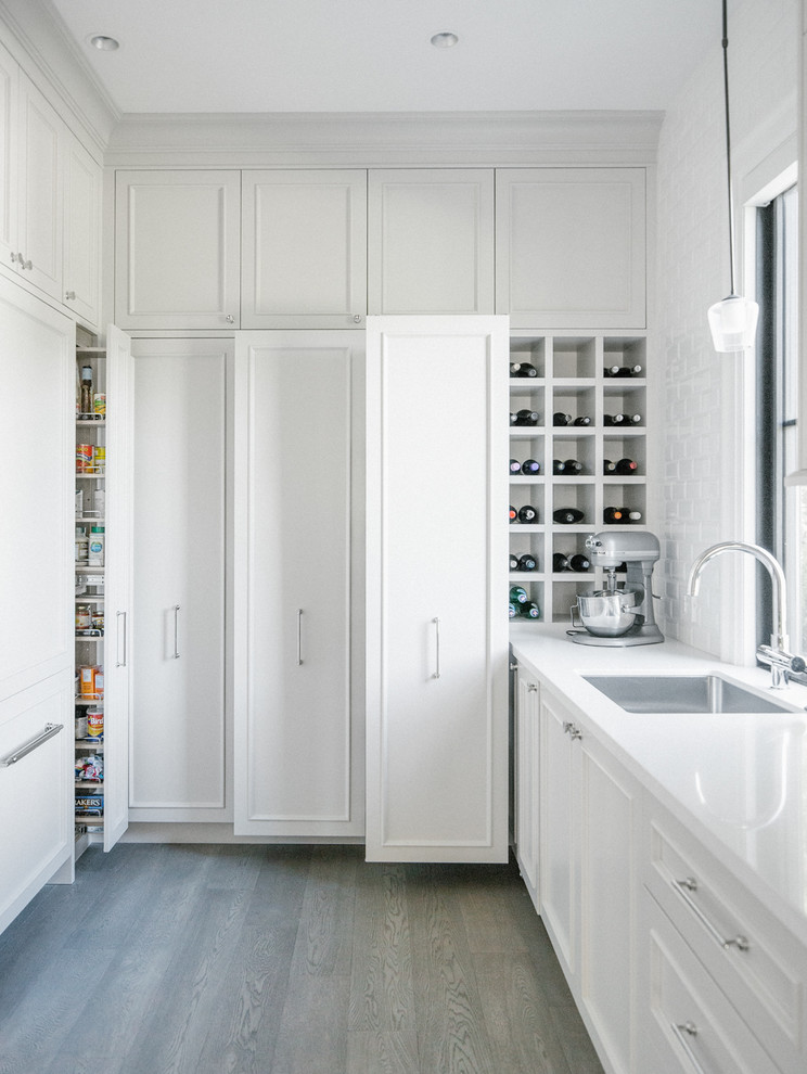 This is an example of a traditional kitchen in Vancouver with a submerged sink, beaded cabinets, white cabinets and white splashback.