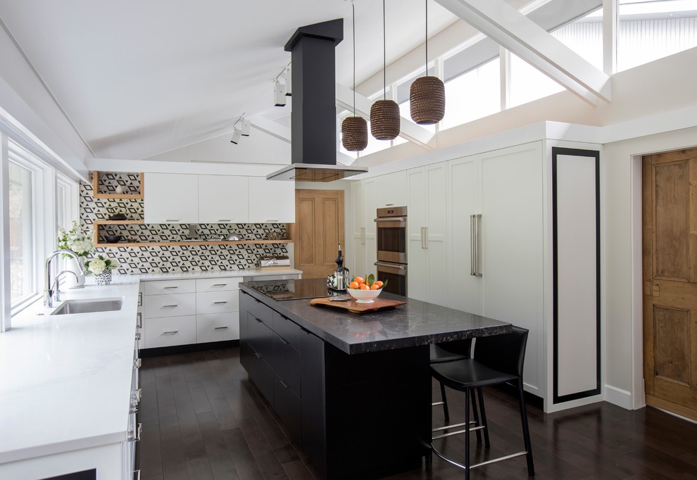 Idéer för att renovera ett stort 60 tals vit vitt u-kök, med skåp i shakerstil, svarta skåp, bänkskiva i kvarts, svart stänkskydd, stänkskydd i marmor, integrerade vitvaror, mörkt trägolv, en köksö och brunt golv