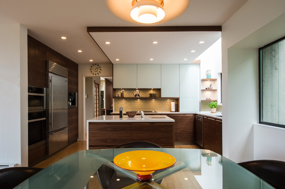 Example of a mid-sized eclectic u-shaped bamboo floor and beige floor eat-in kitchen design in Vancouver with an undermount sink, flat-panel cabinets, dark wood cabinets, quartz countertops, green backsplash, glass tile backsplash, stainless steel appliances and an island
