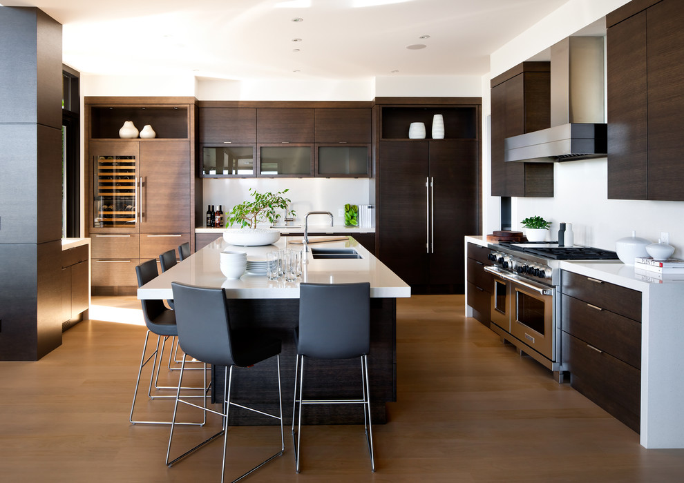 Moderne Küche in U-Form mit Doppelwaschbecken, flächenbündigen Schrankfronten, dunklen Holzschränken, Küchenrückwand in Weiß und Küchengeräten aus Edelstahl in Vancouver