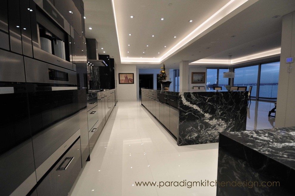 Inspiration for an expansive contemporary galley open plan kitchen in Vancouver with a submerged sink, flat-panel cabinets, dark wood cabinets, granite worktops, black splashback, stone slab splashback, integrated appliances, porcelain flooring and an island.