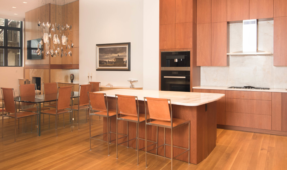 Cette image montre une grande cuisine ouverte linéaire vintage en bois brun avec un placard à porte plane, une crédence blanche, un électroménager noir, un sol en bois brun et îlot.
