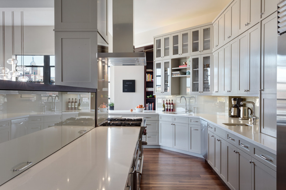 Klassische Küche in L-Form mit Schrankfronten im Shaker-Stil, grauen Schränken, Küchenrückwand in Weiß, dunklem Holzboden und Kücheninsel in New York