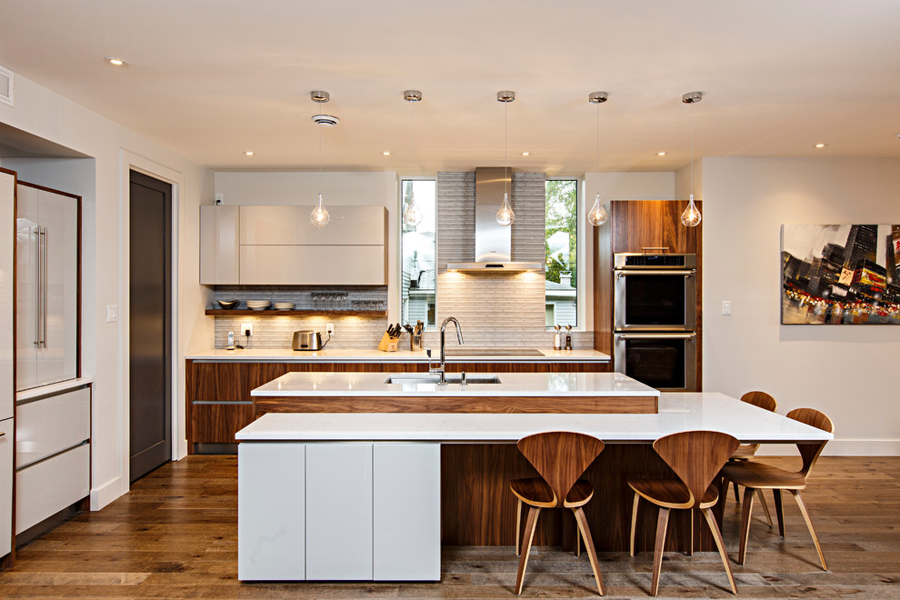 Kitchen - mid-sized contemporary l-shaped medium tone wood floor kitchen idea in Ottawa with an undermount sink, flat-panel cabinets, white cabinets, quartzite countertops, gray backsplash, glass tile backsplash, stainless steel appliances and an island