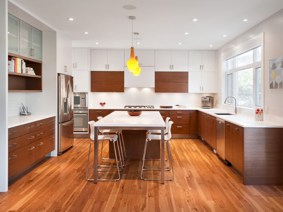 Moderne Küche in L-Form mit Unterbauwaschbecken, flächenbündigen Schrankfronten, hellbraunen Holzschränken, Küchenrückwand in Weiß und Küchengeräten aus Edelstahl in Ottawa