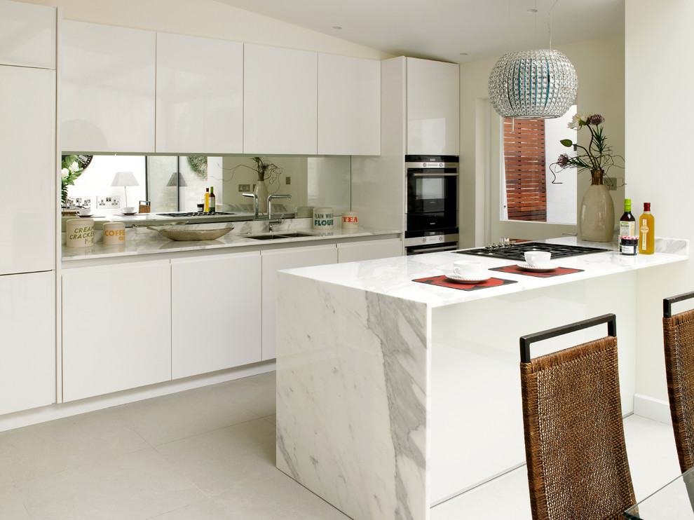 Inredning av ett modernt mellanstort kök, med en undermonterad diskho, släta luckor, marmorbänkskiva, spegel som stänkskydd, rostfria vitvaror, klinkergolv i keramik, en halv köksö och vita skåp