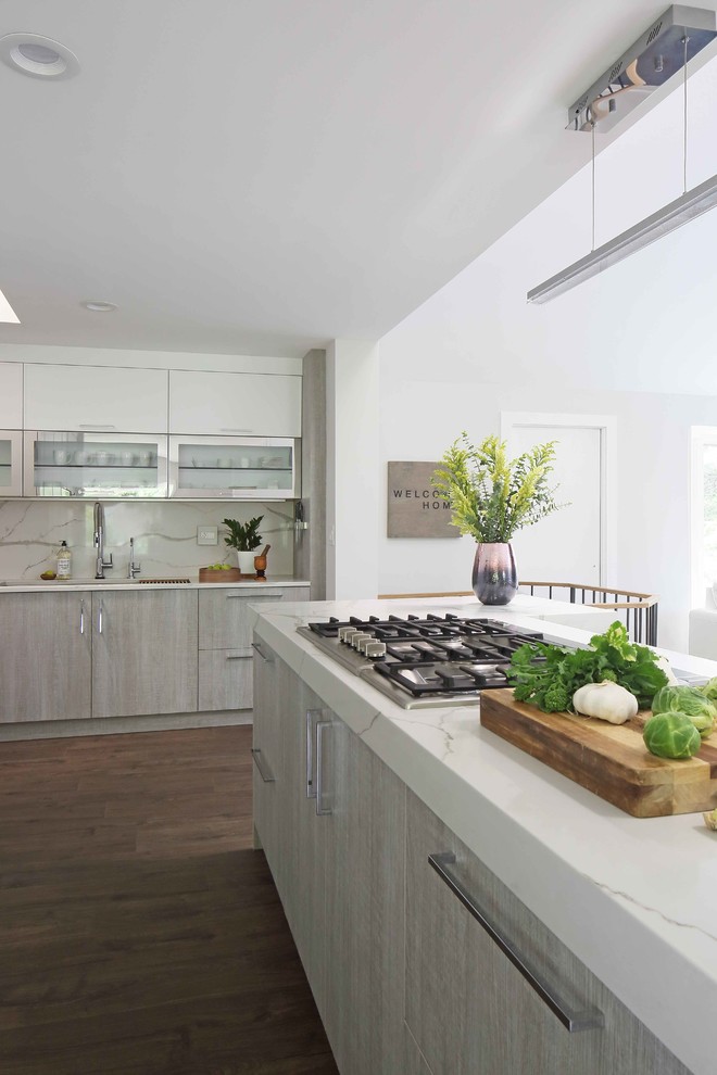 Inspiration for a large modern galley vinyl floor open concept kitchen remodel in New York with an undermount sink, flat-panel cabinets, gray cabinets, quartz countertops, white backsplash, marble backsplash, stainless steel appliances and an island