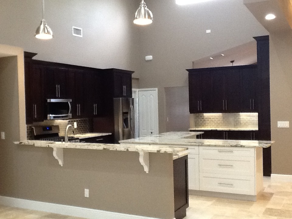 This is an example of an expansive classic u-shaped kitchen/diner in Tampa with a belfast sink, shaker cabinets, dark wood cabinets, granite worktops, metallic splashback, mosaic tiled splashback, stainless steel appliances, travertine flooring and an island.