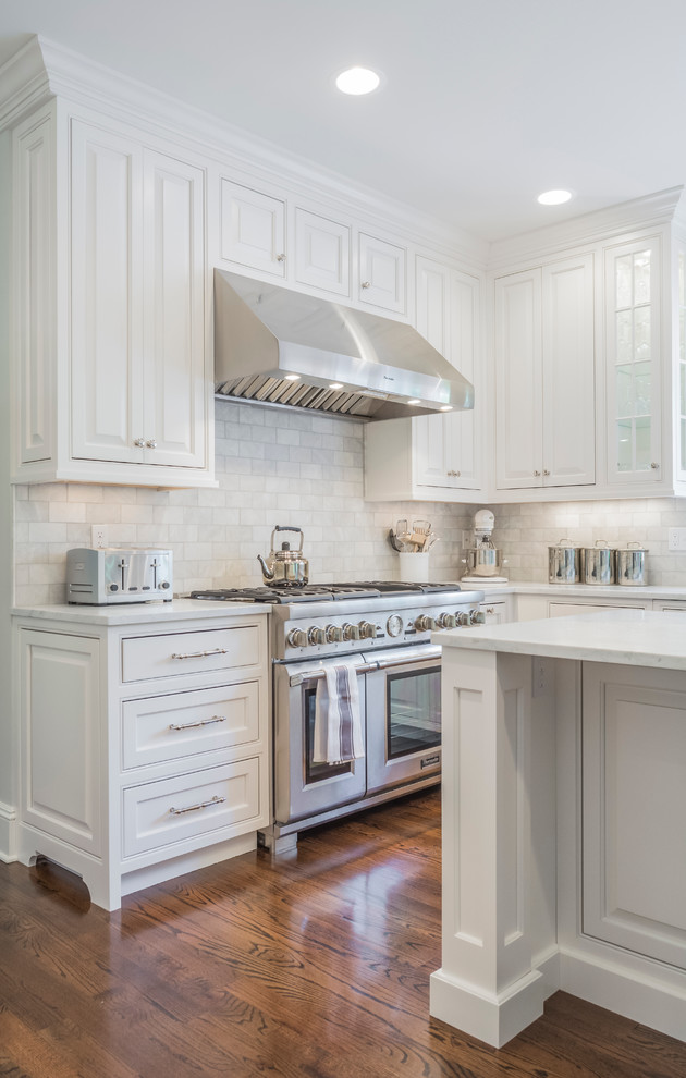 This is an example of a large classic u-shaped kitchen in New York with raised-panel cabinets, white cabinets, marble worktops, dark hardwood flooring and an island.