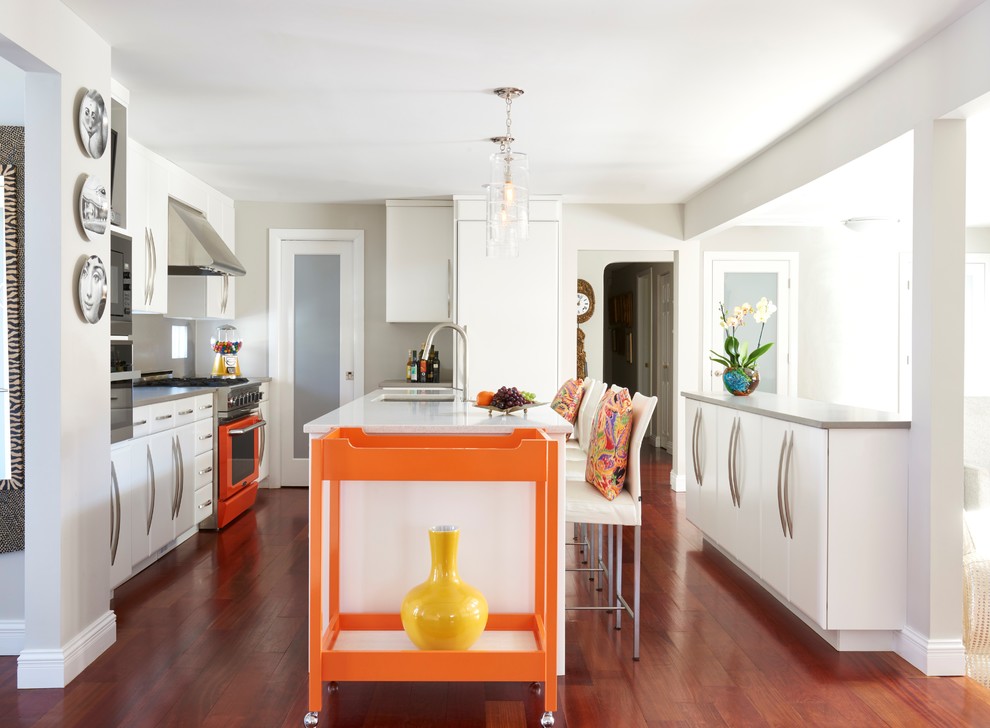 Mid-sized trendy galley brown floor and medium tone wood floor open concept kitchen photo in New York with an undermount sink, flat-panel cabinets, white cabinets, colored appliances, an island and gray backsplash