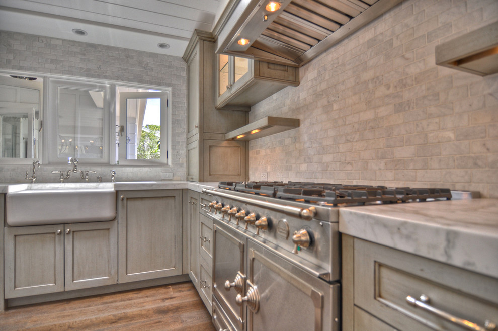 Example of a large country u-shaped medium tone wood floor eat-in kitchen design in Orange County with a farmhouse sink, recessed-panel cabinets, marble countertops, stainless steel appliances, distressed cabinets, gray backsplash, stone tile backsplash and an island