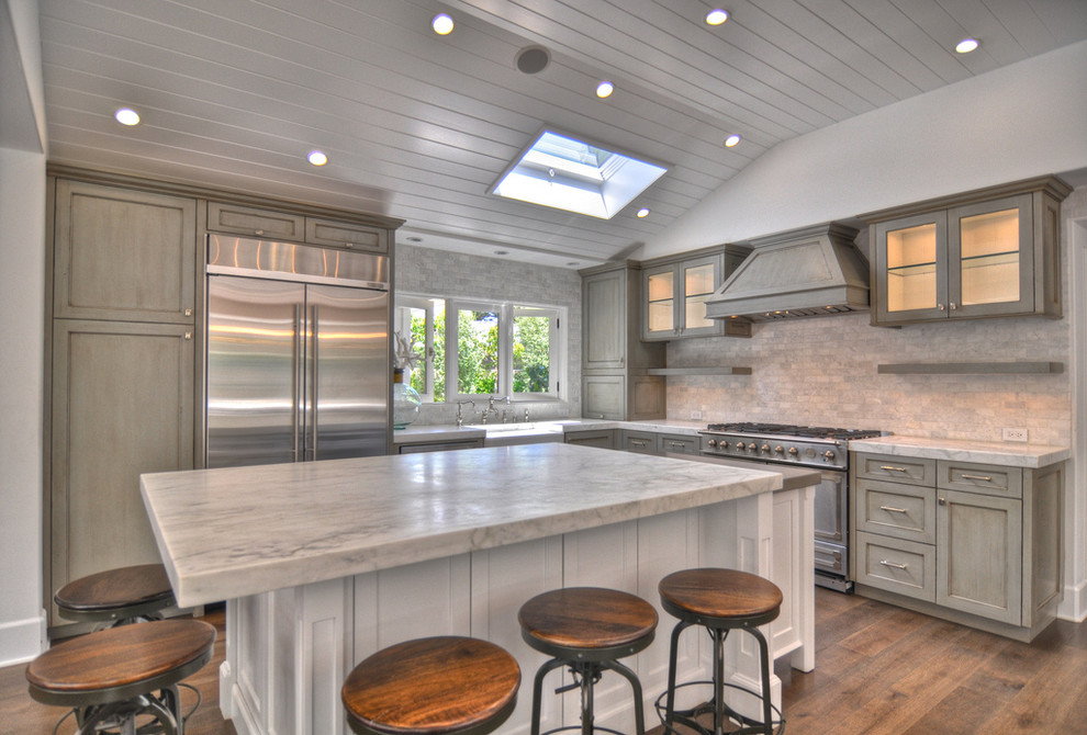Eat-in kitchen - large farmhouse u-shaped medium tone wood floor eat-in kitchen idea in Orange County with a farmhouse sink, recessed-panel cabinets, distressed cabinets, marble countertops, stainless steel appliances, stone tile backsplash, an island and gray backsplash