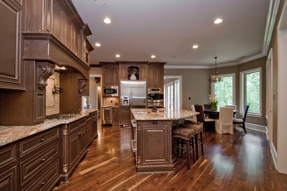 Eat-in kitchen - large rustic u-shaped medium tone wood floor and brown floor eat-in kitchen idea in Little Rock with an undermount sink, raised-panel cabinets, dark wood cabinets, granite countertops, beige backsplash, an island, subway tile backsplash and stainless steel appliances