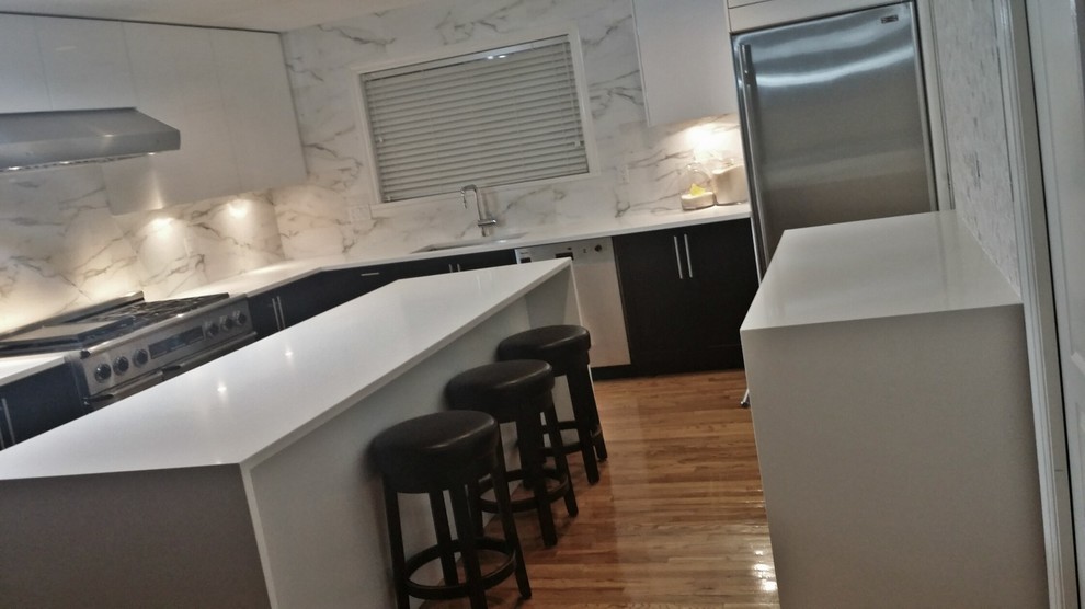 Medium sized contemporary u-shaped kitchen/diner in Vancouver with a submerged sink, flat-panel cabinets, white cabinets, quartz worktops, white splashback, mosaic tiled splashback, stainless steel appliances, light hardwood flooring and an island.