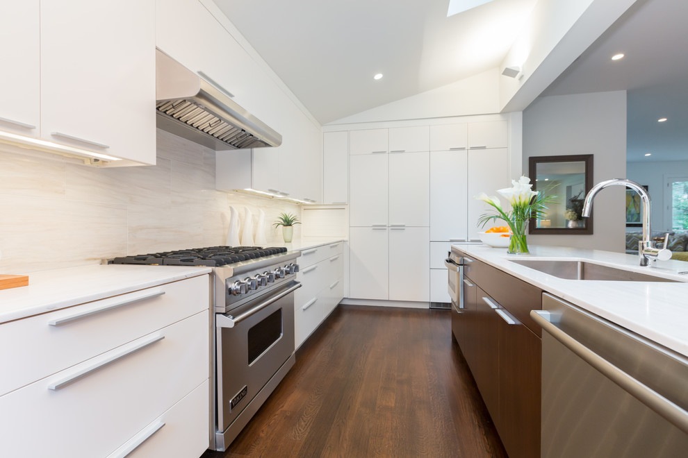 Photo of a contemporary l-shaped kitchen in DC Metro with a submerged sink, flat-panel cabinets, white cabinets, white splashback and stainless steel appliances.