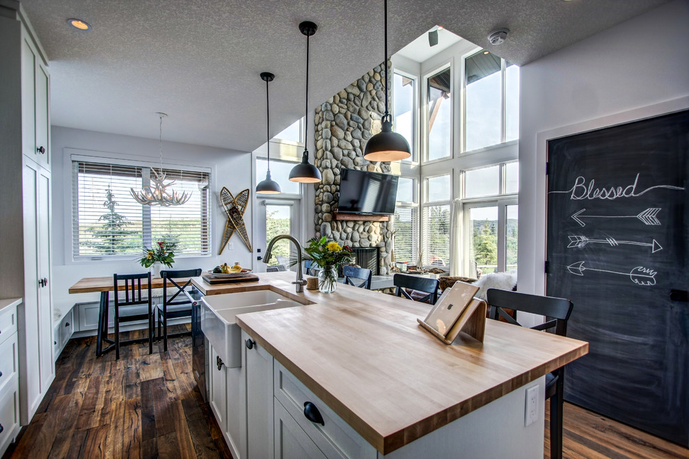Offene, Zweizeilige, Mittelgroße Klassische Küche mit Landhausspüle, Schrankfronten im Shaker-Stil, weißen Schränken, Arbeitsplatte aus Holz, braunem Holzboden und Kücheninsel in Calgary
