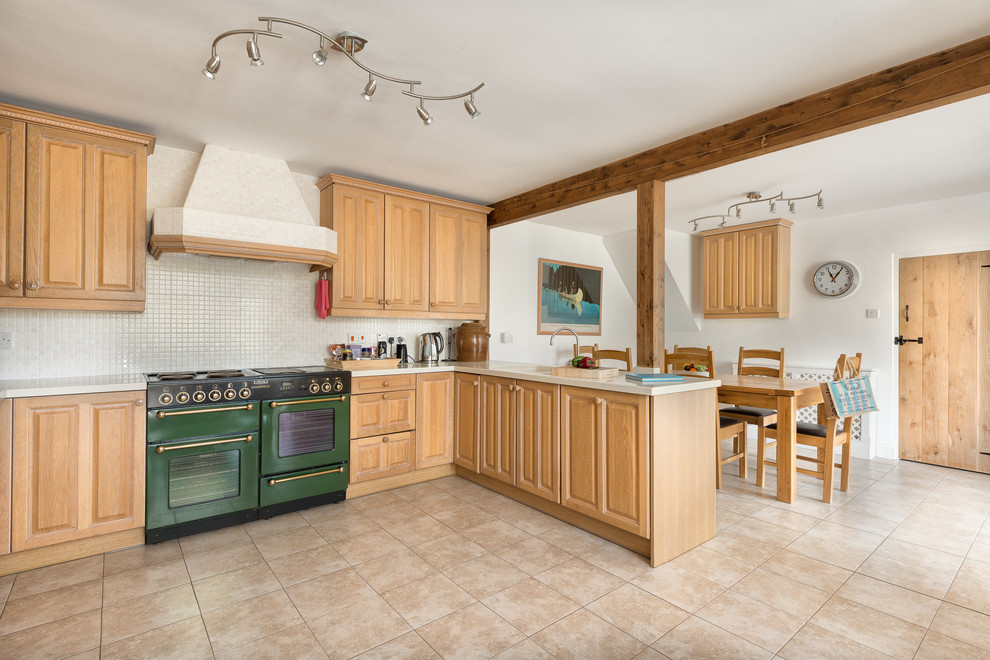 Design ideas for a farmhouse l-shaped kitchen/diner in Devon with raised-panel cabinets, light wood cabinets, laminate countertops, white splashback, ceramic splashback, coloured appliances and ceramic flooring.