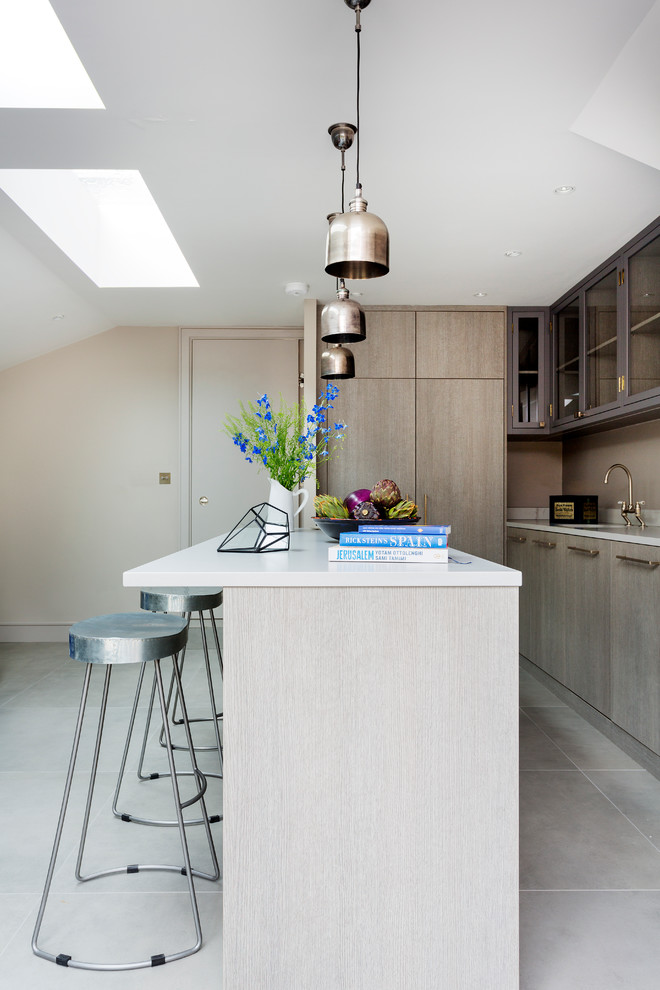 This is an example of a large contemporary l-shaped kitchen/diner in London with flat-panel cabinets, medium wood cabinets, marble splashback, stainless steel appliances and an island.