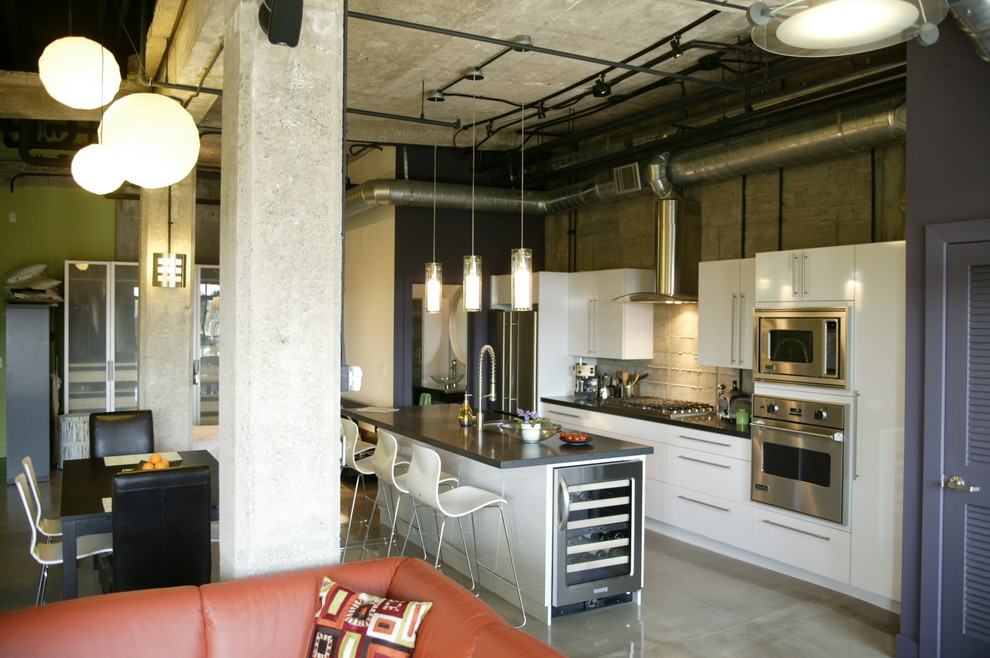 Foto di una cucina contemporanea con lavello sottopiano, ante lisce, ante bianche, paraspruzzi grigio, elettrodomestici in acciaio inossidabile e pavimento in cemento