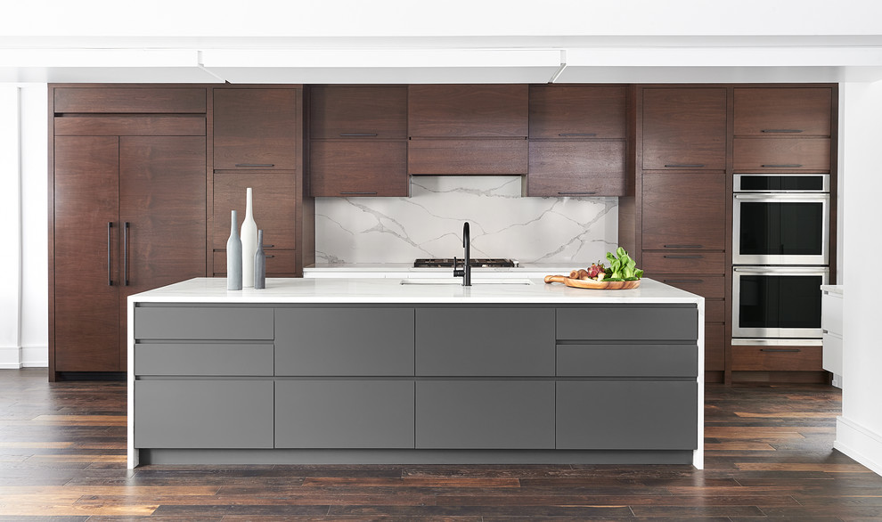 Inspiration for an expansive contemporary galley open plan kitchen in Toronto with a submerged sink, flat-panel cabinets, dark wood cabinets, engineered stone countertops, white splashback, stone slab splashback, integrated appliances, dark hardwood flooring, an island and white worktops.