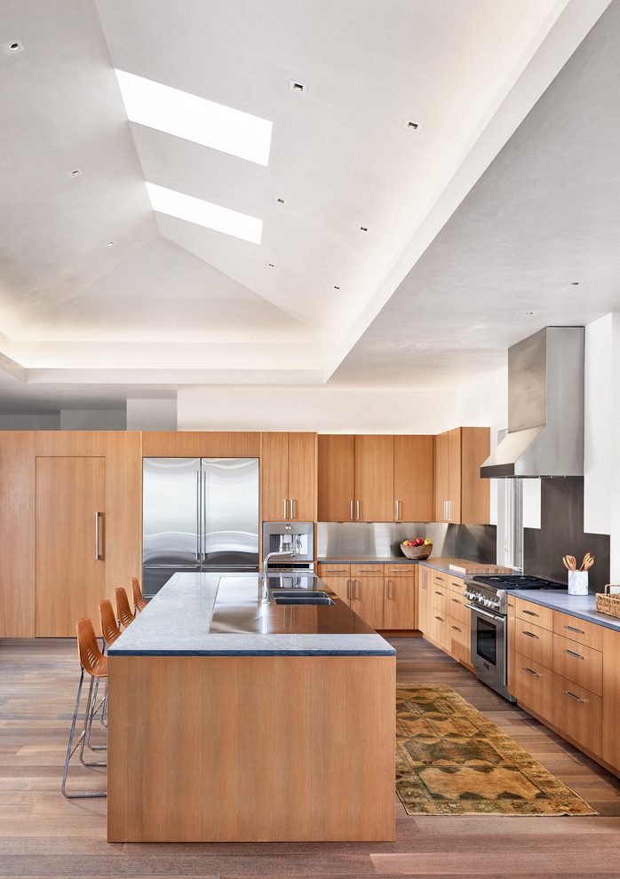 Inspiration for a contemporary l-shaped kitchen in Austin with a double-bowl sink, flat-panel cabinets, medium wood cabinets, metallic splashback, stainless steel appliances, medium hardwood flooring and an island.