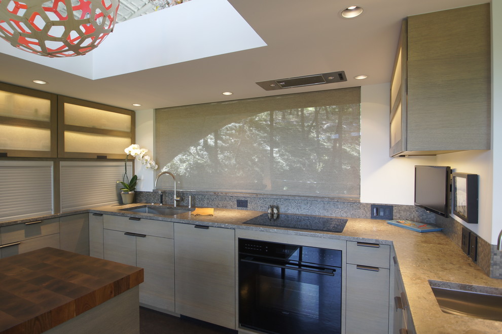 Bild på ett mellanstort, avskilt funkis u-kök, med en enkel diskho, släta luckor, grå skåp, bänkskiva i kalksten, flerfärgad stänkskydd, stänkskydd i mosaik, integrerade vitvaror, korkgolv och en köksö