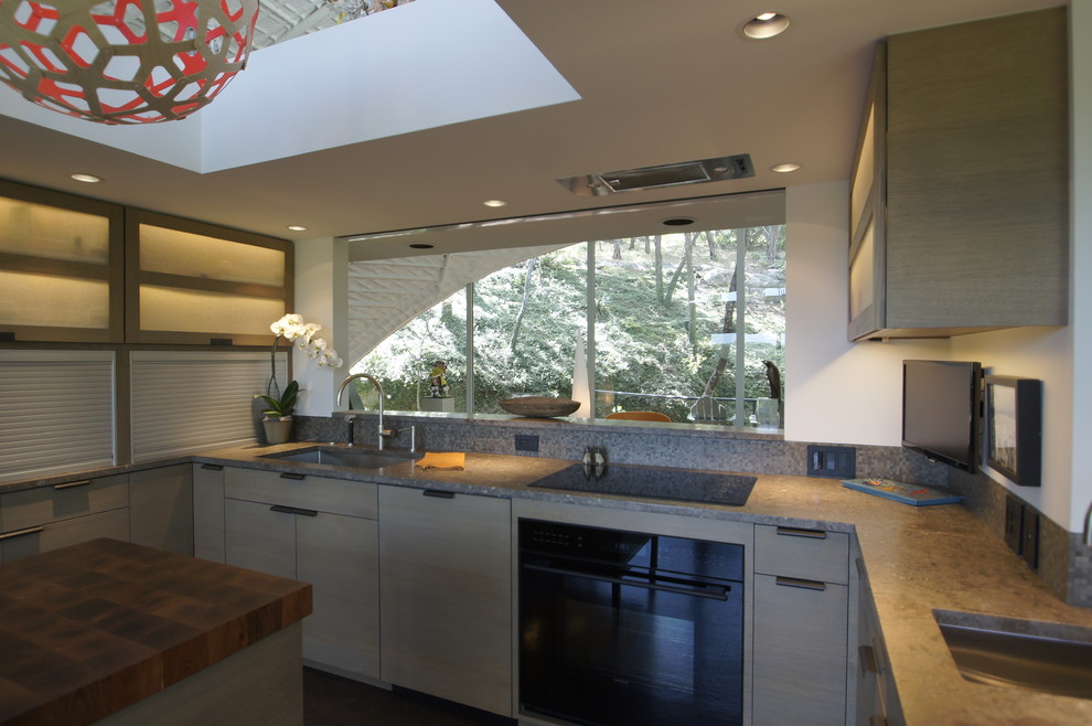Exempel på ett mellanstort, avskilt modernt u-kök, med en enkel diskho, släta luckor, grå skåp, bänkskiva i kalksten, flerfärgad stänkskydd, stänkskydd i mosaik, integrerade vitvaror, korkgolv och en köksö