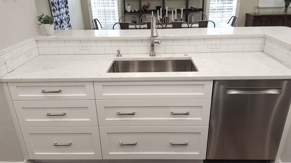 Mid-sized arts and crafts l-shaped medium tone wood floor and brown floor enclosed kitchen photo in Austin with a single-bowl sink, shaker cabinets, white cabinets, quartz countertops, white backsplash, subway tile backsplash, stainless steel appliances, an island and white countertops