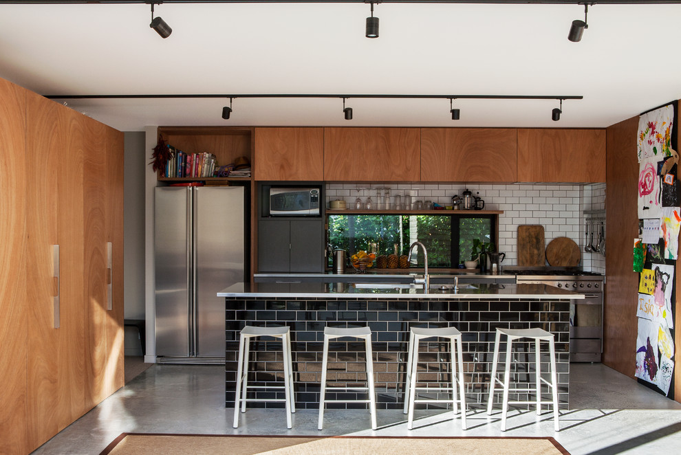 Свежая идея для дизайна: угловая кухня в современном стиле с островом, обеденным столом, двойной мойкой, белым фартуком, фартуком из плитки кабанчик, техникой из нержавеющей стали и бетонным полом - отличное фото интерьера