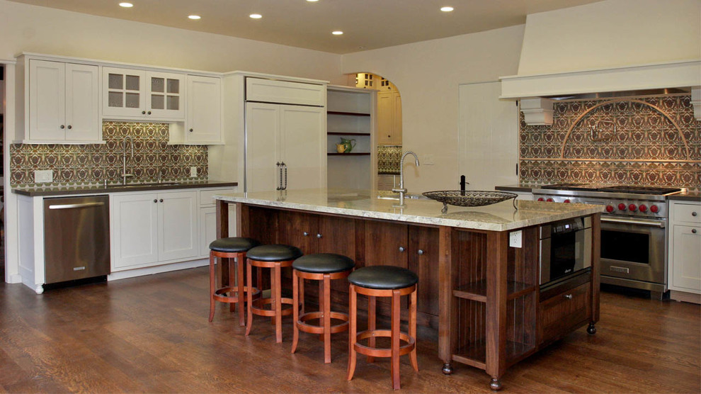 Foto på ett stort medelhavsstil kök, med en undermonterad diskho, luckor med infälld panel, vita skåp, stänkskydd i keramik, rostfria vitvaror, mellanmörkt trägolv och en köksö