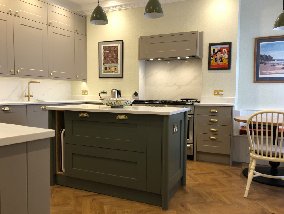 This is an example of a medium sized coastal kitchen/diner in London with a double-bowl sink, recessed-panel cabinets, grey cabinets, quartz worktops, white splashback, stone slab splashback, stainless steel appliances, vinyl flooring, an island, brown floors and white worktops.