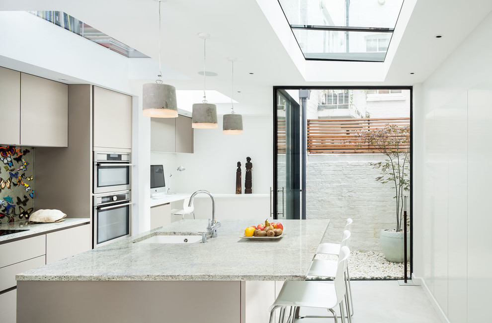 Пример оригинального дизайна: параллельная кухня в современном стиле с врезной мойкой, плоскими фасадами, серыми фасадами, разноцветным фартуком, техникой из нержавеющей стали, бетонным полом и островом