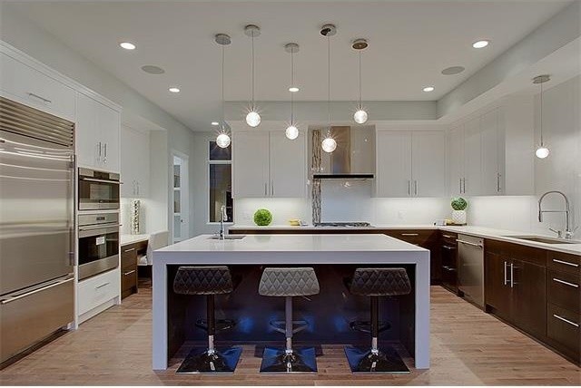 Esempio di una grande cucina minimalista con ante lisce, ante bianche, top in quarzo composito, elettrodomestici in acciaio inossidabile e parquet chiaro