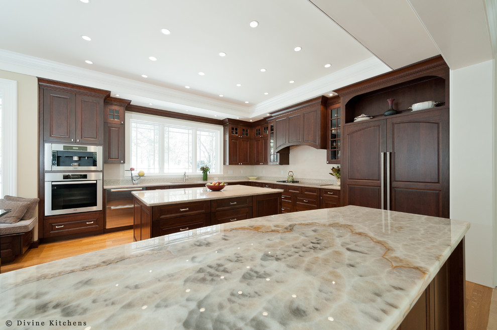 Design ideas for a large classic u-shaped kitchen/diner in Boston with a submerged sink, raised-panel cabinets, dark wood cabinets, beige splashback, stainless steel appliances, light hardwood flooring, multiple islands and quartz worktops.
