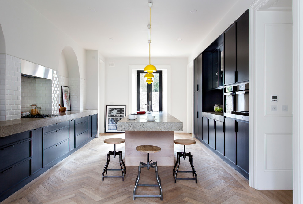 Immagine di una cucina design con ante lisce, ante nere, top in cemento e parquet chiaro