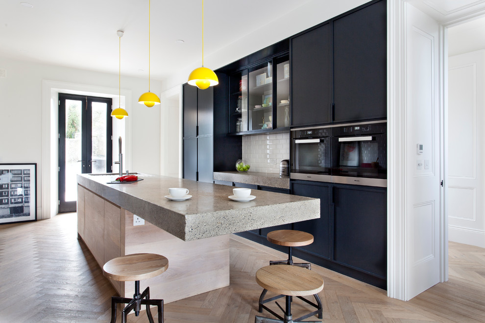 Esempio di una cucina contemporanea con ante lisce, ante nere, top in cemento e parquet chiaro