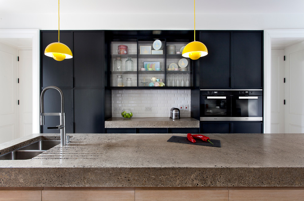 Zweizeilige Moderne Küche mit flächenbündigen Schrankfronten, schwarzen Schränken, Betonarbeitsplatte, hellem Holzboden und Kücheninsel in Dublin