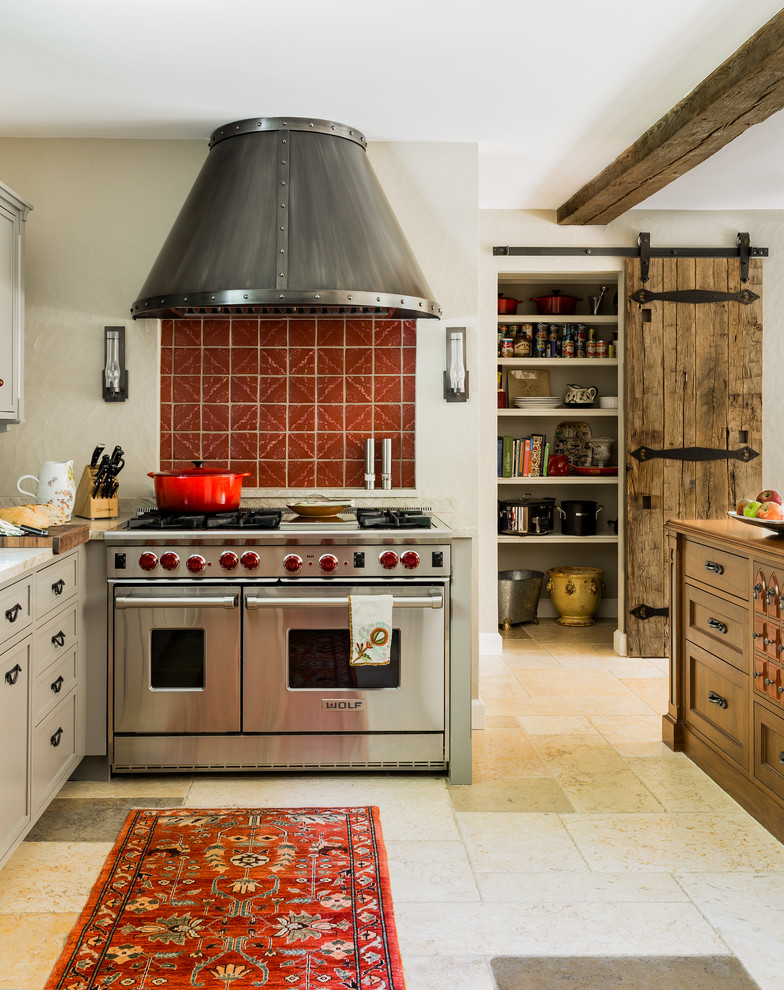 Foto på ett medelhavsstil kök, med luckor med profilerade fronter, grå skåp, marmorbänkskiva, rött stänkskydd, stänkskydd i terrakottakakel, rostfria vitvaror, kalkstensgolv och en köksö