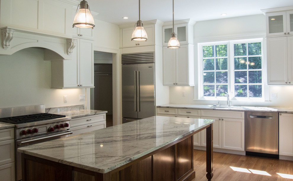 Enclosed kitchen - large transitional u-shaped light wood floor enclosed kitchen idea in Boston with a double-bowl sink, flat-panel cabinets, white cabinets, marble countertops, white backsplash, stainless steel appliances and an island